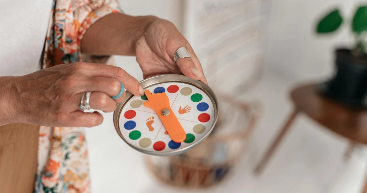 A hand holding a small round game spinner with colored dots