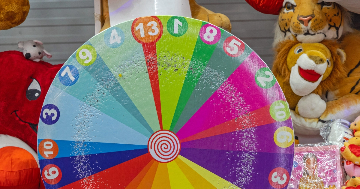 A colorful carnival prize wheel with numbered slices, surrounded by stuffed animals